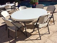 Full view of round table and six chairs set up outdoors by pool