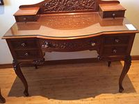 Front three-quarter view showing overall form, carved details, and glass top