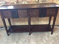 Front view of Pier One console table showing three drawers with metal knobs, vertical groove detailing, and lower shelf.