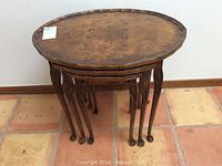 Nested set of three burled walnut tables stacked together, view highlighting wood grain and leg design.