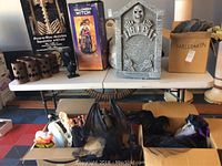 Wide view showing skeleton box, witch box, tombstone, lanterns and boxes of assorted Halloween decor
