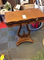 Closed antique wooden card table showing curved edges and carved pedestal base.