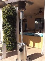 Full view of the Nexgrill outdoor heater standing next to a patio with a protective domed top and stainless steel body, showing height and general condition.