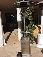 Full view of the Kirkland patio heater outdoors showing the stainless steel finish, base with wheels, and heat reflector on top.