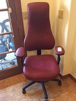 Front view of the burgundy high backed office chair with padded seat, backrest, and armrests, showing adjustable features.