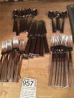 Full overview of stainless steel cutlery set arranged by type on wood surface.