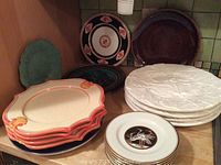 Full set of various serving plates including white chargers, floral Horchow plates, a Wedgewood plate, and Fitz and Floyd porcelain plates.