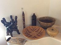 Lot with multiple African decor items including baskets, carved sculpture, candle holder, and wooden decor