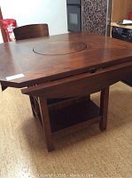 Full view of square wooden games table with one chair and shelves underneath