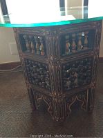 Side view of wooden table base showing carved and inlaid geometric patterns and small turned spindles details