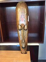 Full frontal view of the carved wooden mask showing intricate design and painted elements.