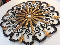Top-down view of the wrought iron chandelier medallion showing the full circular sunburst leaf and scroll design with gold accent highlights.