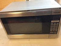 Front view of Panasonic microwave oven showing stainless steel body, black tinted door with viewing window, and digital display panel