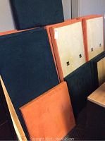 Orange and navy sound baffles leaning against a wall, showing size and fabric texture.