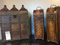 Photo of three wine bottle carriers: two wicker for one bottle each, and one wooden for three bottles
