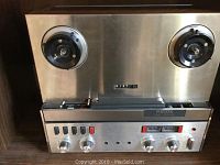 Front view of Revox stainless steel reel deck showing reel posts, transport controls, VU meters and knobs