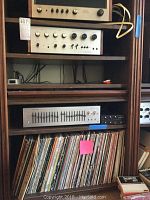 Stacked stereo components on wooden shelf with LP records below