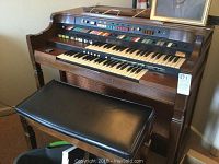 Front view of Hammond organ console showing dual keyboards, preset tabs and matching padded bench
