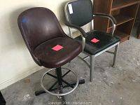 Black office chair with arms with metal frame and two brown swivel bar stools with metal bases and cushioned seats, one stool partially visible on left.