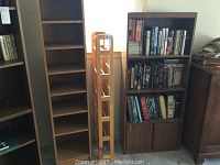 Tall 8-shelf dark laminate bookshelf standing next to light wood media rack and medium laminate bookshelf with cabinet doors.