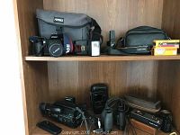 Top shelf photo showing Canon EOS Rebel S camera with Fotima camera bag, Sunpak flash, two Canon 110ED cameras, Kodak Gold film boxes, and black case.