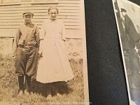 Close-up of a vintage black and white photo showing a man and a woman posing outdoors in period clothing.