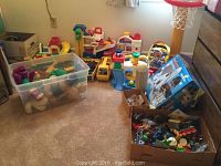 Assorted Fisher Price, Little Tikes, and other preschool toys scattered on the floor with boxes and playsets visible