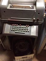 Front side view of the Teletype machine showing the keyboard with round keys and some red keys.