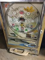 Front view of vintage Pachinko machine with metal and glass construction and circular pin setup.