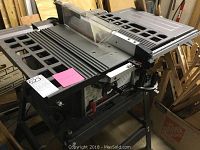 Side view of table saw on folding stand with surrounding workshop materials