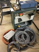 Large metal electrical box with multiple power outlets, wiring cables coiled below, and additional components on top of the box.