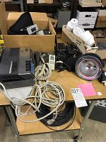 Wooden cart with electronic equipment and accessories spread on top and wires hanging down.