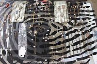 Top-down view of brass and crystal necklaces spread out on zebra pattern surface, showing multiple gold and silver tone chains with crystal pendants and embellishments.