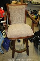 Vintage swivel chair with brown wood frame and beige fabric upholstery, showing seat and backrest