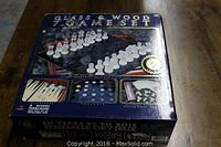 Box of the 7 game set showing images of glass and wood chess pieces, checkers, and backgammon with a label indicating glass and wood materials.