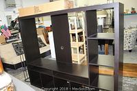Full view of the dark brown IKEA TV stand, showing multiple compartments and shelves.