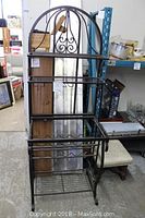 Full view of metal wine rack showing its arched top, multiple shelves, and hangers for wine glasses