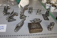 Overview of 9 assorted pewter figurines including birds on bases, sitting animal or cherub, horse rider figurine, and pewter trinket box.