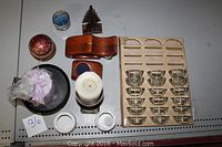 Full view showing multiple types of candlesticks and candles arranged on a table: glass holders, pillar candle, wrapped candle, spherical candle, small dishes, and decorative items.