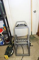 Photo showing Suncast hose organizer reel, Yardworks leaf blower, and rake next to door