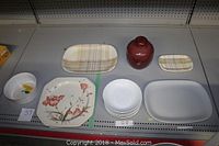 Overview of assorted serving platters, bowls, jar, and baking ware displayed on shelf