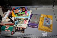 Overview photo showing various board games stacked on a shelving unit including Risk, Monopoly, Taboo, and others