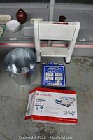 White step ladder, metal bucket, blue woven tarp 4x6, and boxed Outbound 2-person raft with built-in 3-can cooler on shelf