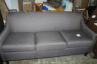 Full view of gray upholstered 3-cushion couch showing overall design and condition