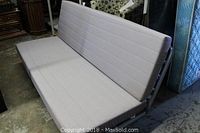 Grey futon couch fully upright as couch, showing length and cushion stitching detail.
