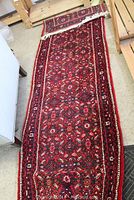 Full view of red hand-knotted runner rug laid out on floor showing overall design and condition.