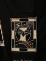 Front view of leaded stained glass window hanging depicting a winking owl with cream, brown, and dark blue stained glass in a rectangular frame.