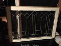Front view of the rectangular white wooden window frame with clear leaded glass showing diamond and linear geometric patterns.