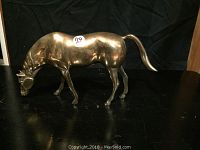 Full view of the brass horse figurine showing its grazing posture and size relative to background.
