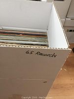 Box containing 65 records stacked vertically, showing the records inside the box.